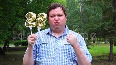 大个子拿着金色气球，把28号放在户外。 28周年庆祝晚会